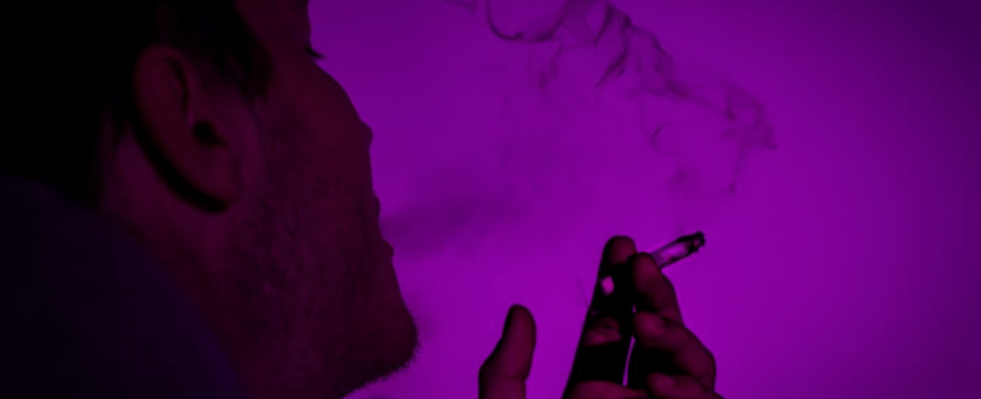 Close up of man smoking a cigarette with purple overlay