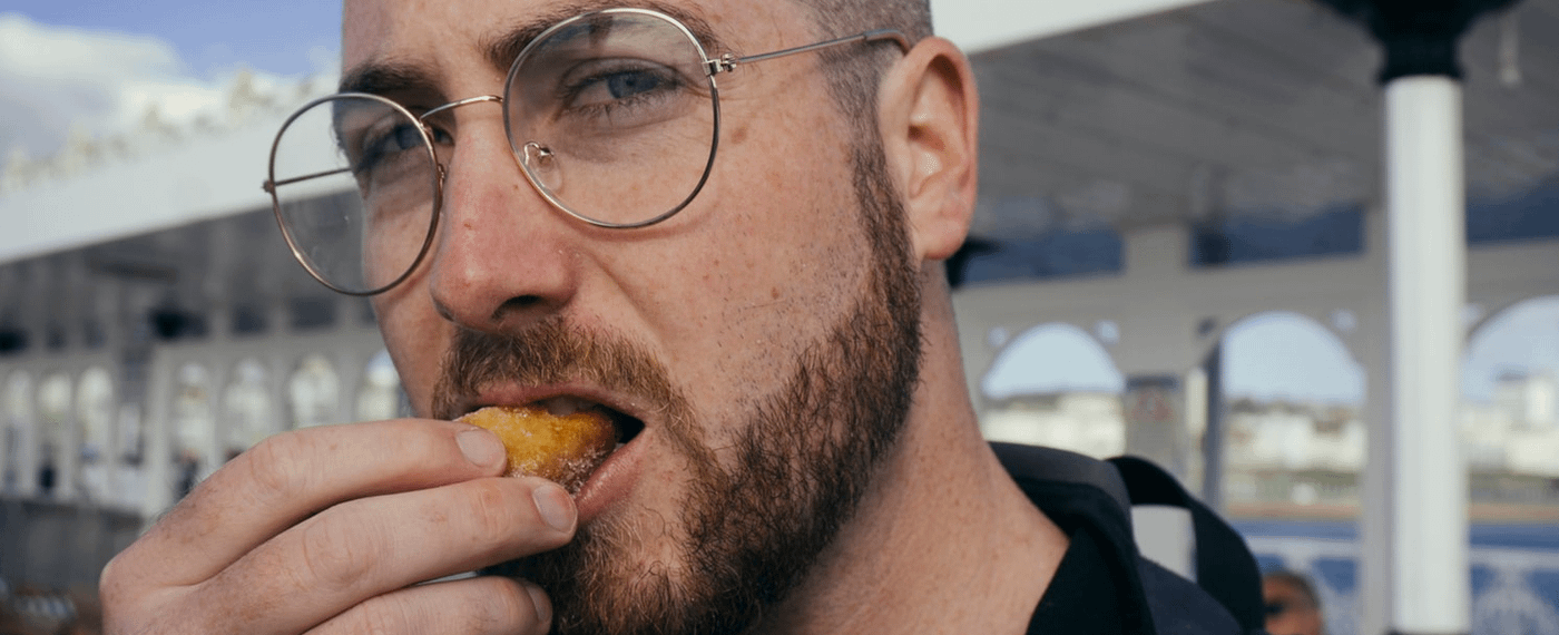 Bearded man with glasses taking a bite of food