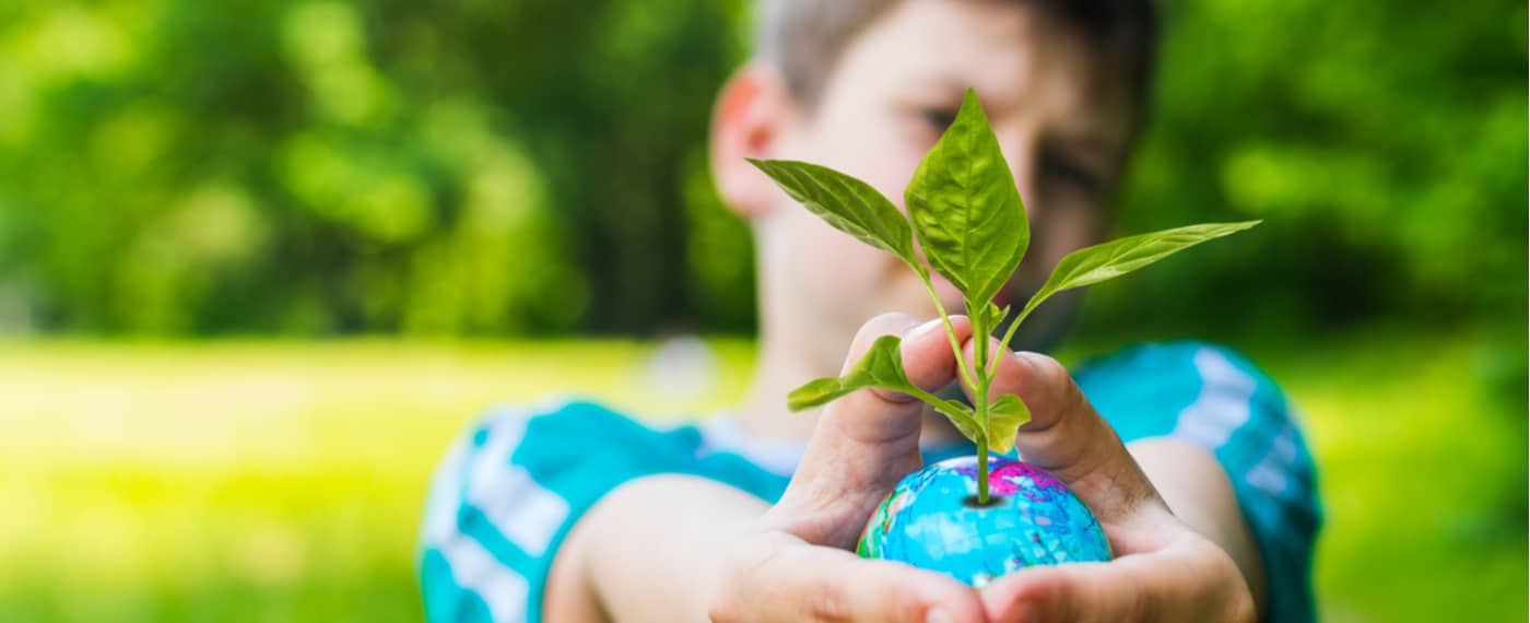 Young boy holding a globe with a plant sprout