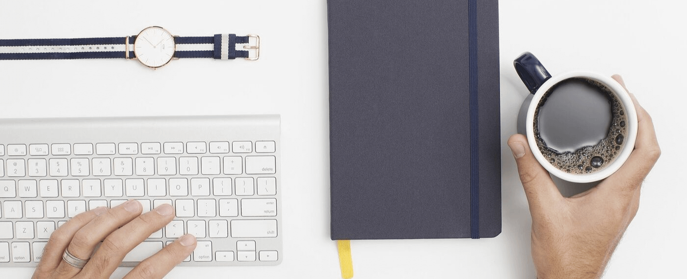 Aerial view of work desk with keyboard, notebook and coffee