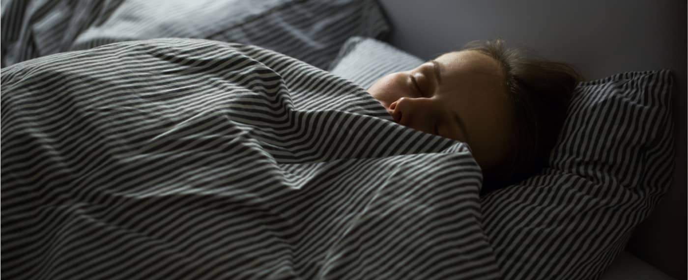 Woman sleeping under striped blankets