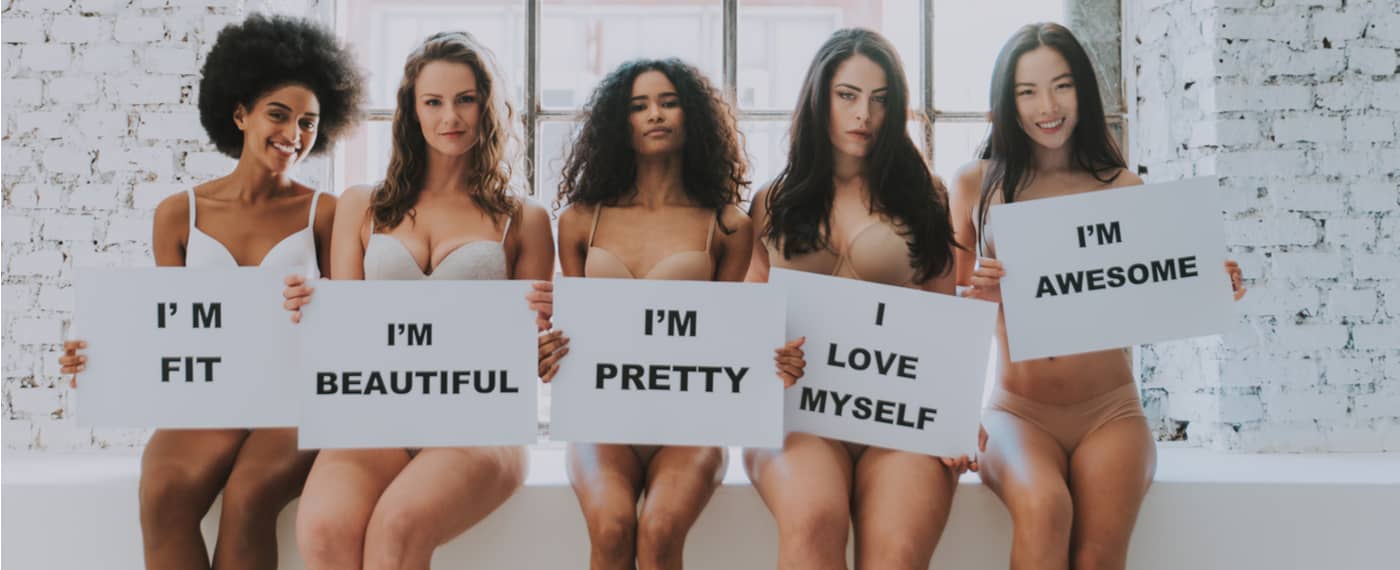 Five women holding up signs with positive self image quotes