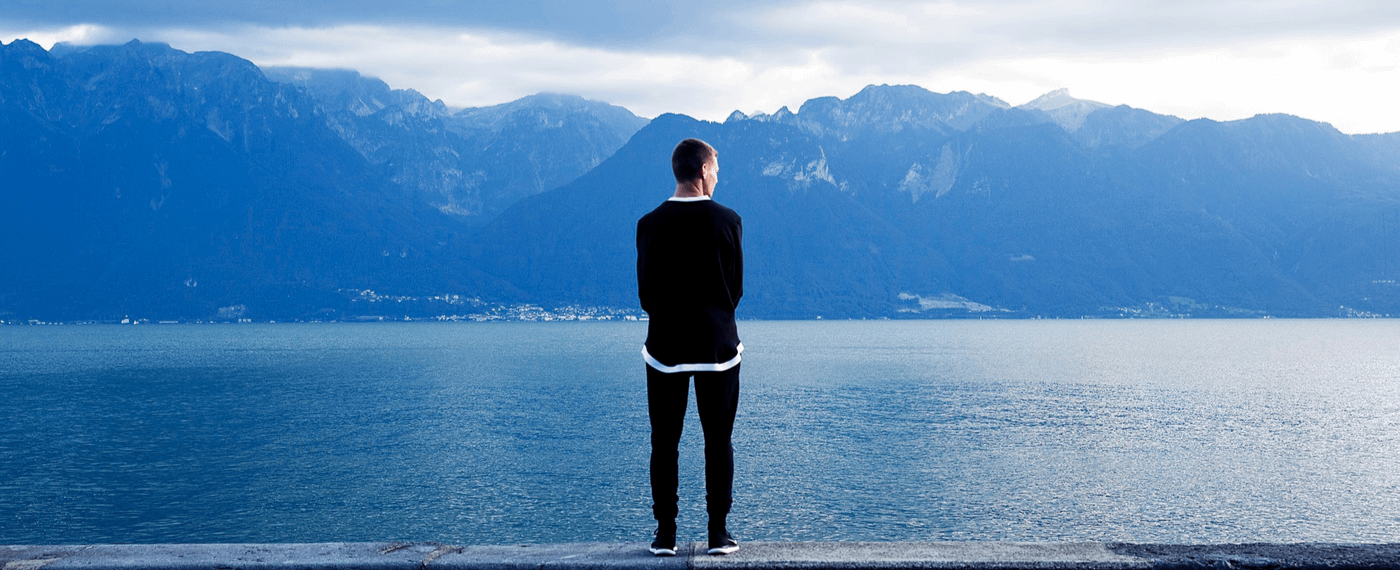 Man looking out over lake and mountains