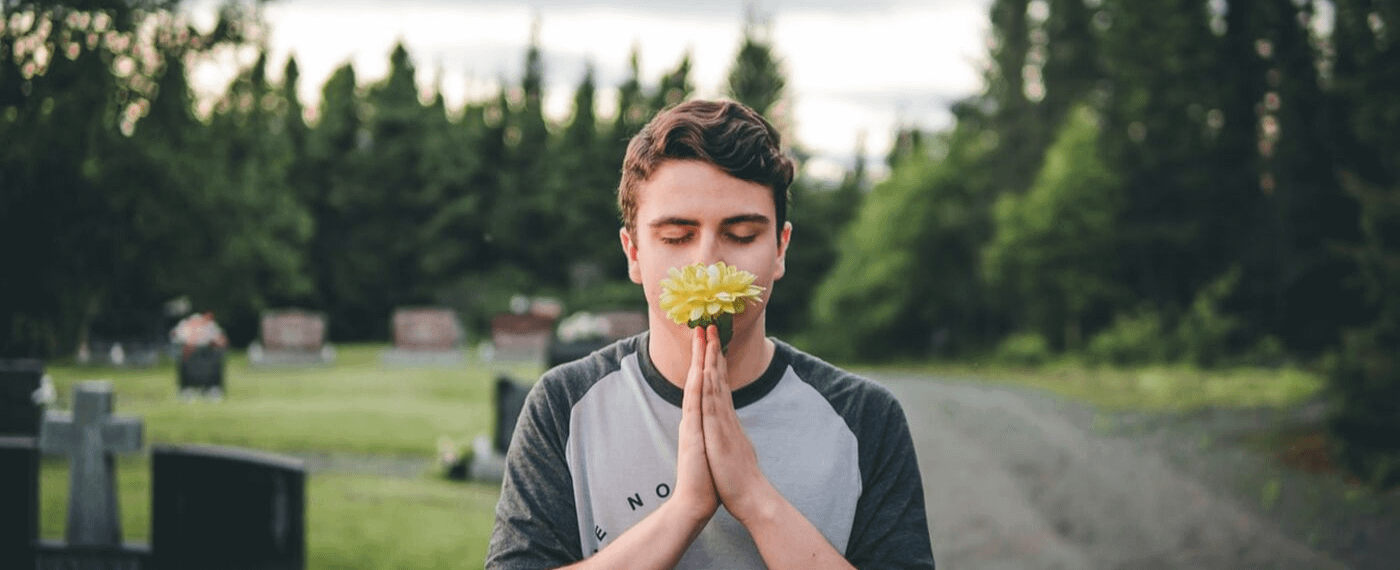 Young man with his eyes closed smelling a yellow flower