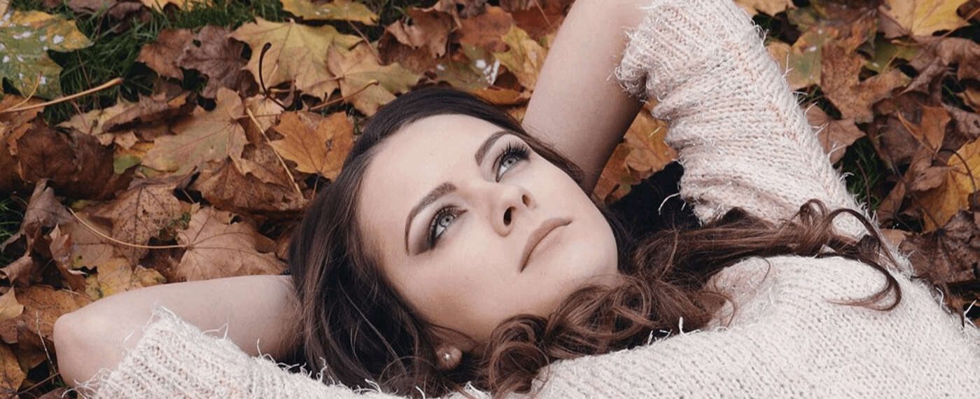 Dark haired woman laying in a pile of leaves