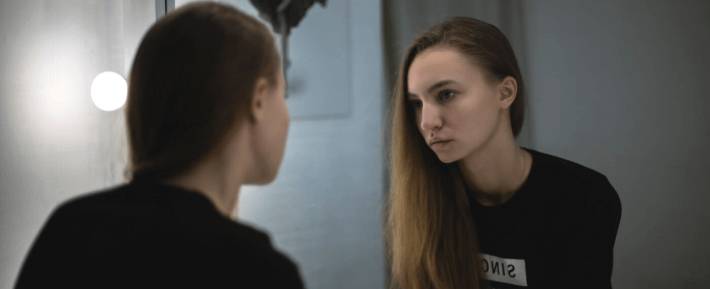 Young woman staring at herself in the mirror