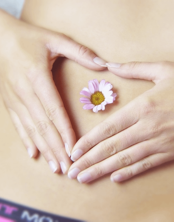 woman holding hands over belly button with a daisy flower in the middle