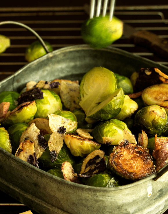 An iron skillet with roasted brussel sprouts with shallots and sunchokes