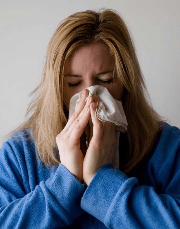 Woman holding a napkin to her nose after sneezing
