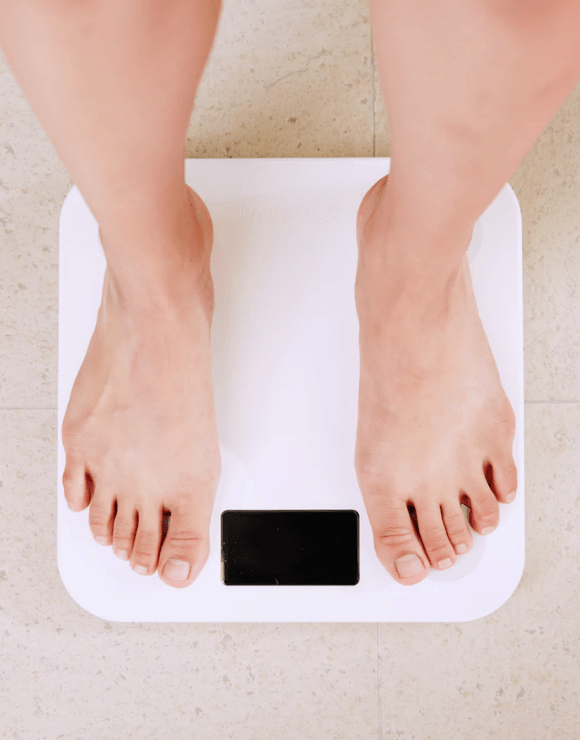 Bare feet standing on top of a scale used for measuring weight