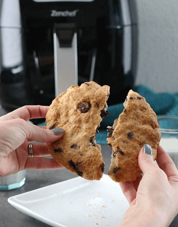 A large air fried vegan chocolate chip cookie being broken in half