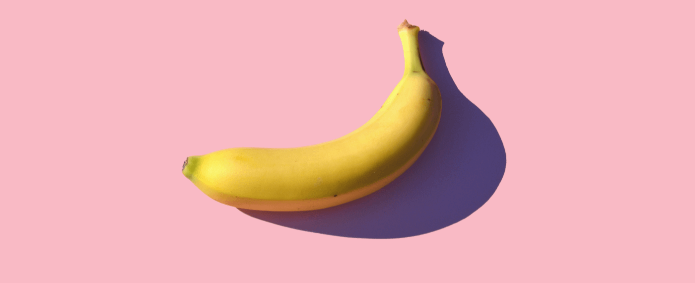 a yellow banana against a pink background