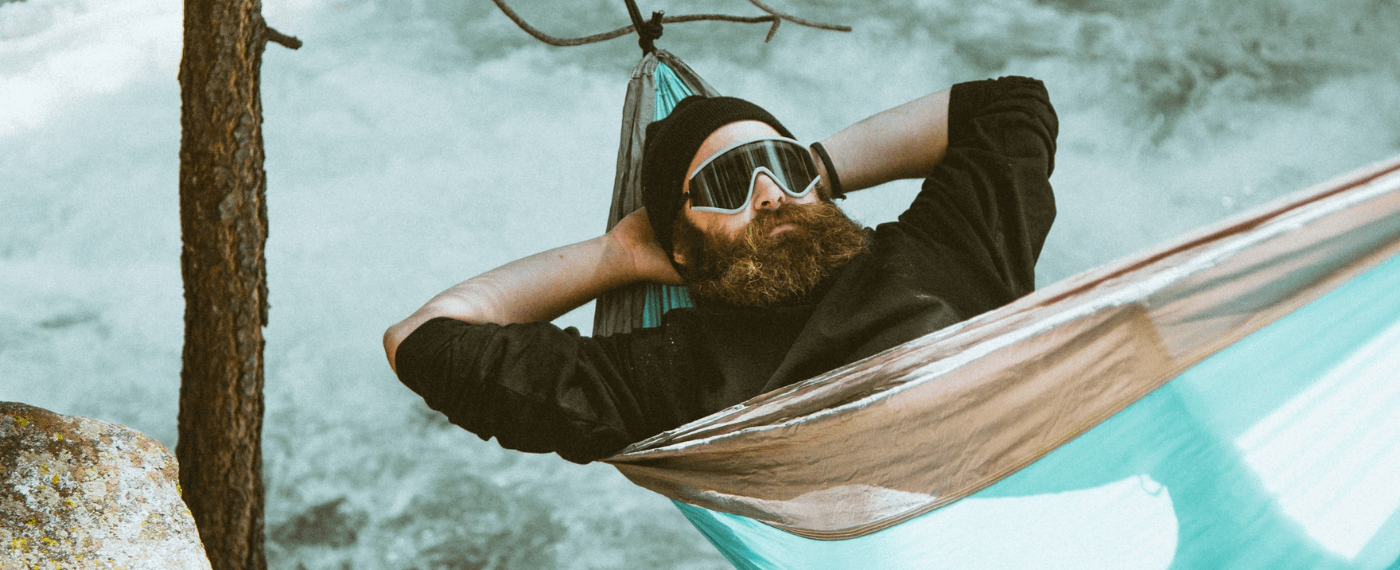 Bearded man relaxing in a hammock in snowy forest