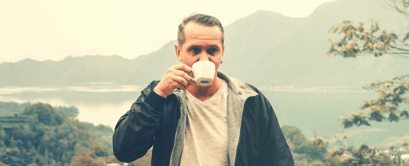 Man drinking a cup of coffee outdoors to help with breathing