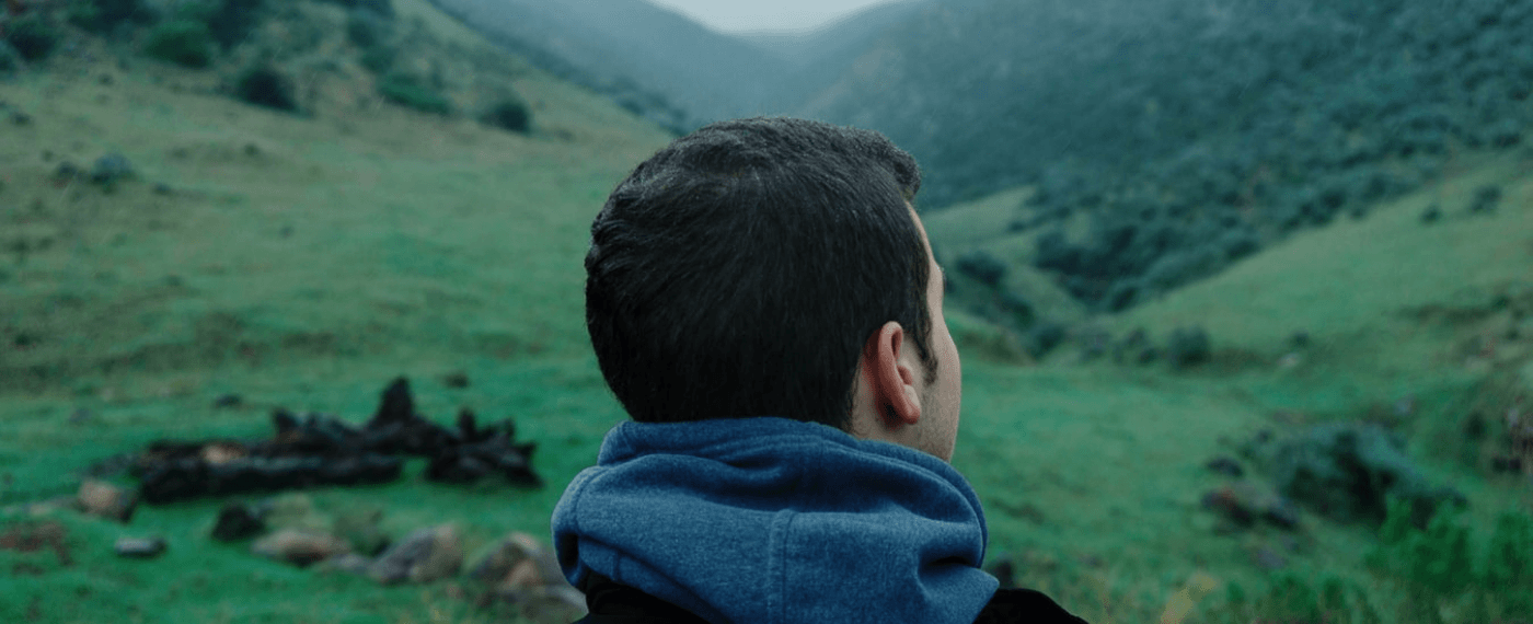man staring out at green pastures thinking about the environment