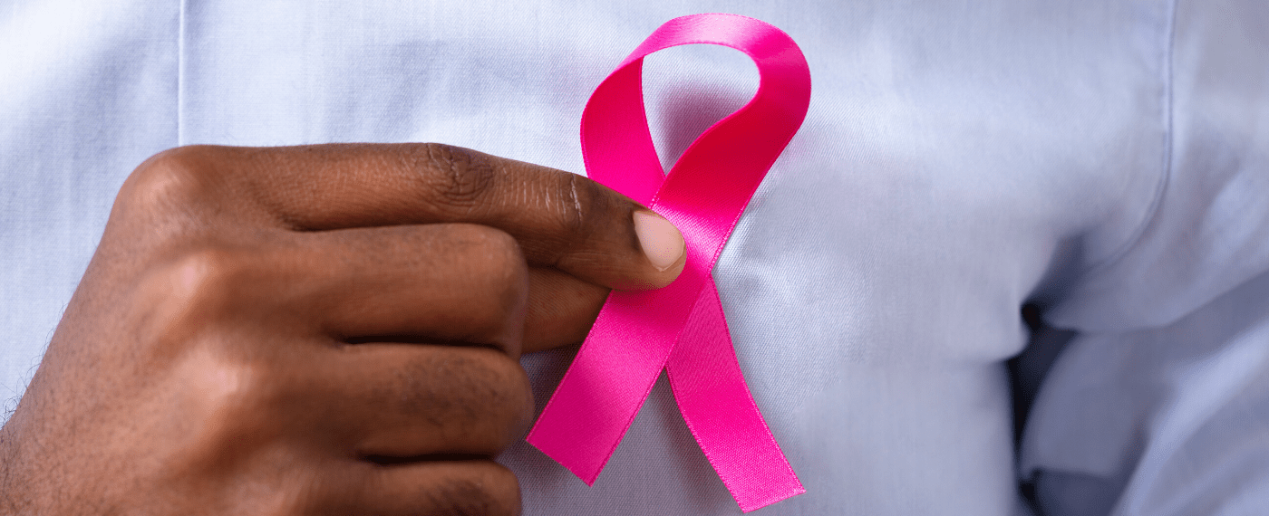 breast cancer ribbon being pinned onto the front of a shirt