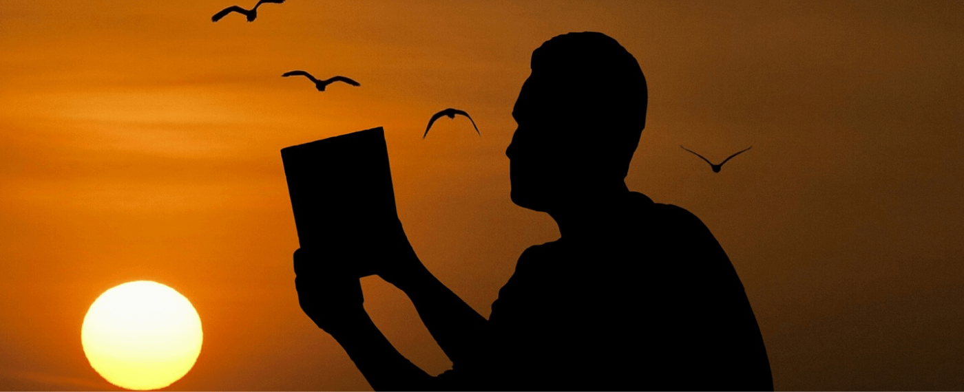 shadow of a man reading a book during sunset
