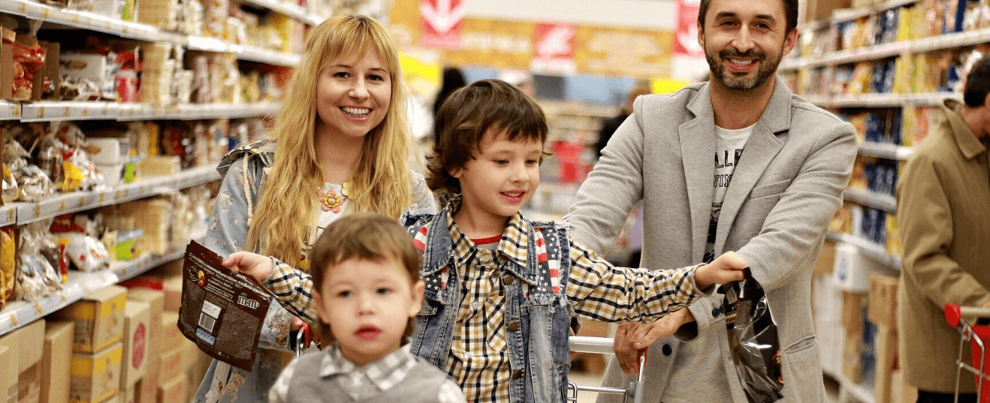 Family pushing kids in shopping cart through black friday deals