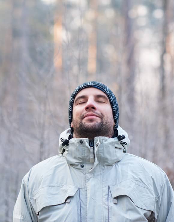 Man in winter gear taking in a deep breathe to relieve holiday stress