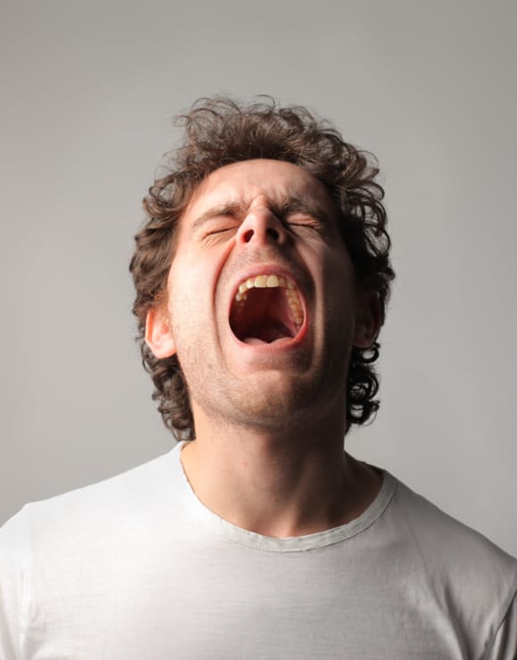 Man leaning head back and yawning largely