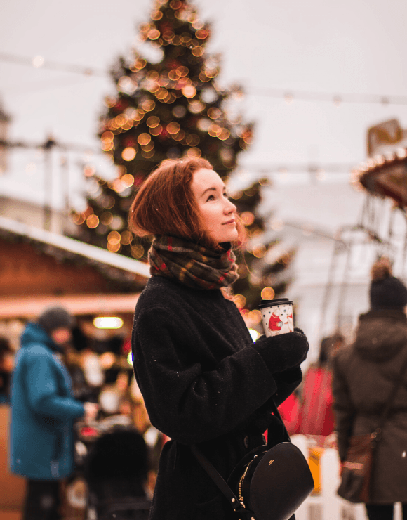 Young girl in winter clothes holding warm coffee to help ease holiday stress