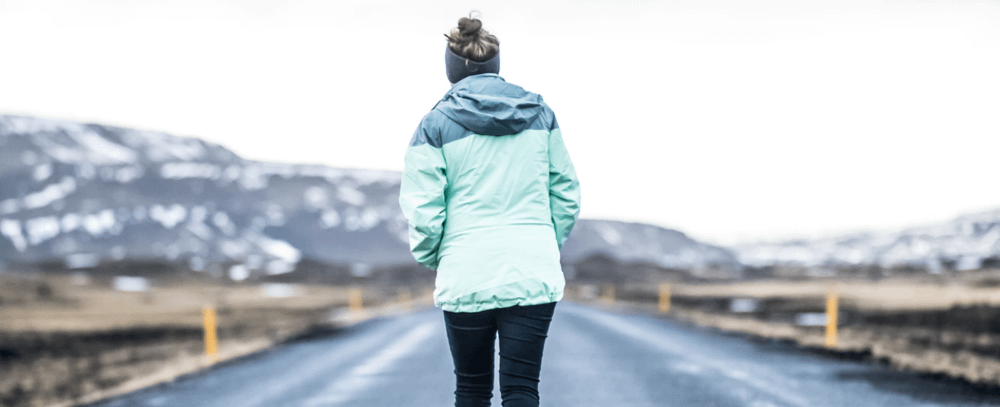 A woman jogs along a snowy road fueled by her winter workout playlist