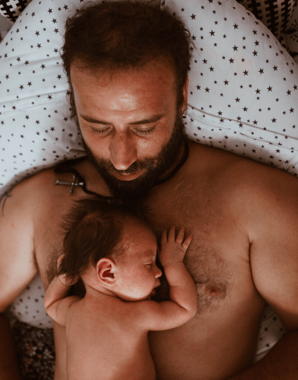 Father with newborn child asleep on top of his chest
