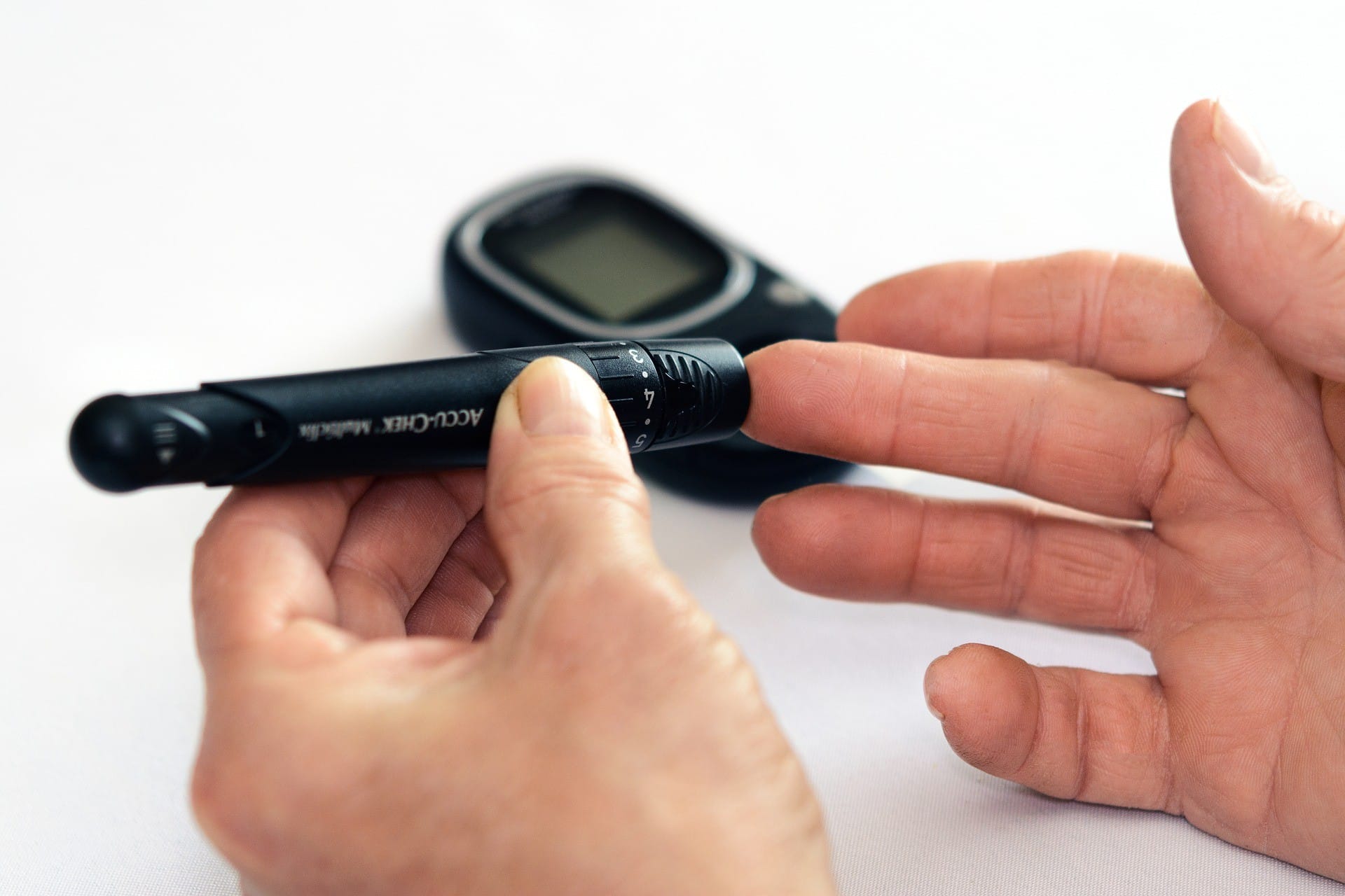 Diabetic male pricking his fingertip with a needle to check blood sugar levels