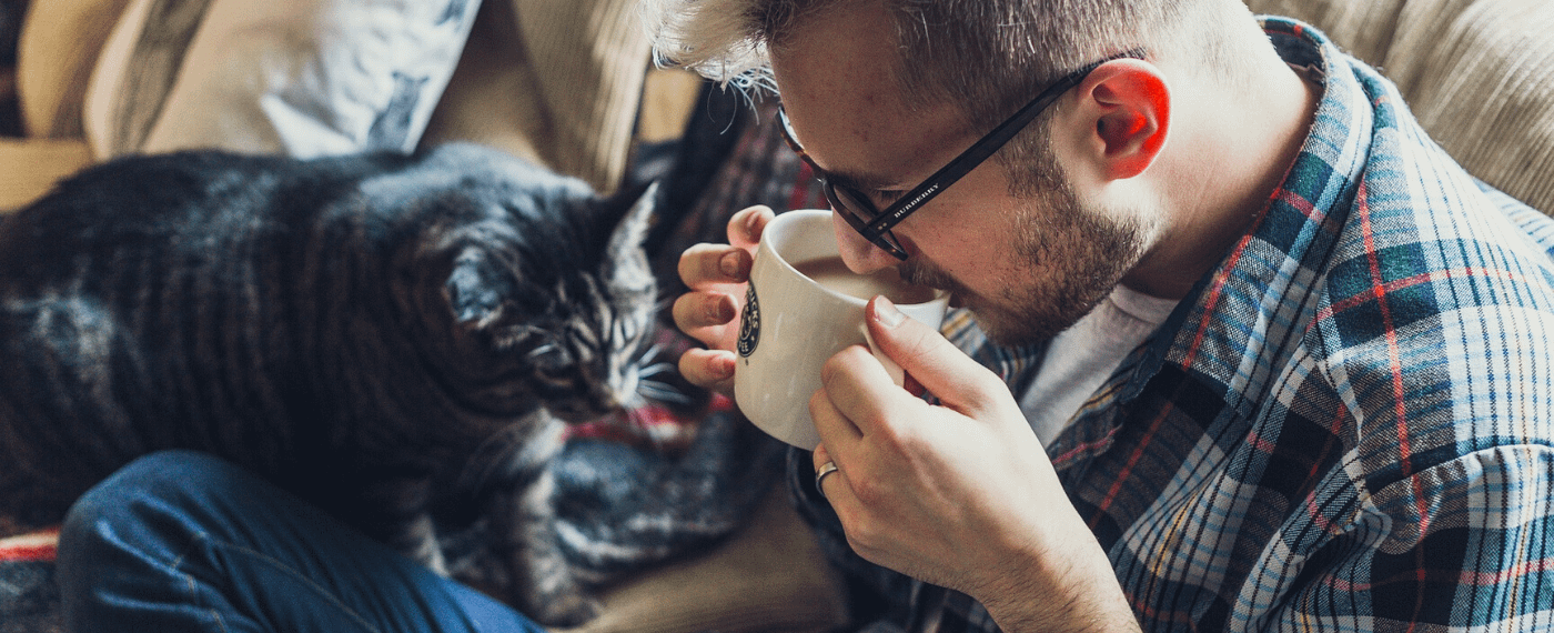 A man sips coffee with his cat, pondering the meaning of self-care