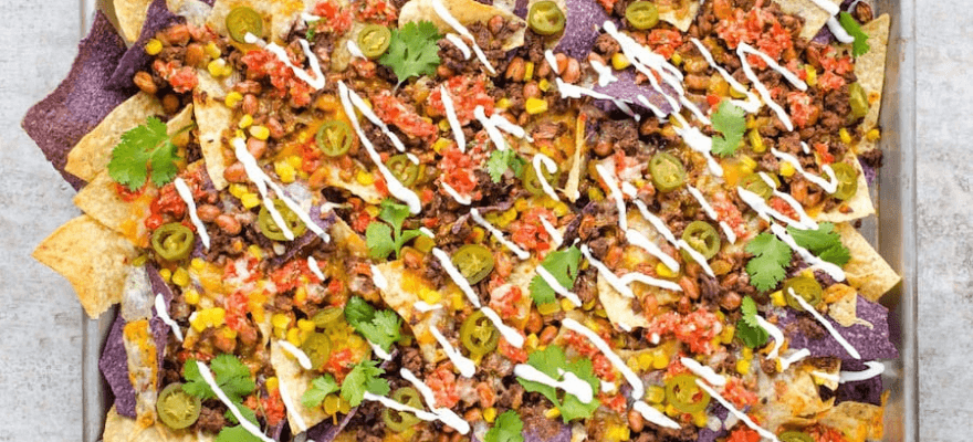 A large tray of loaded healthy nachos with beef and homemade tortilla chips