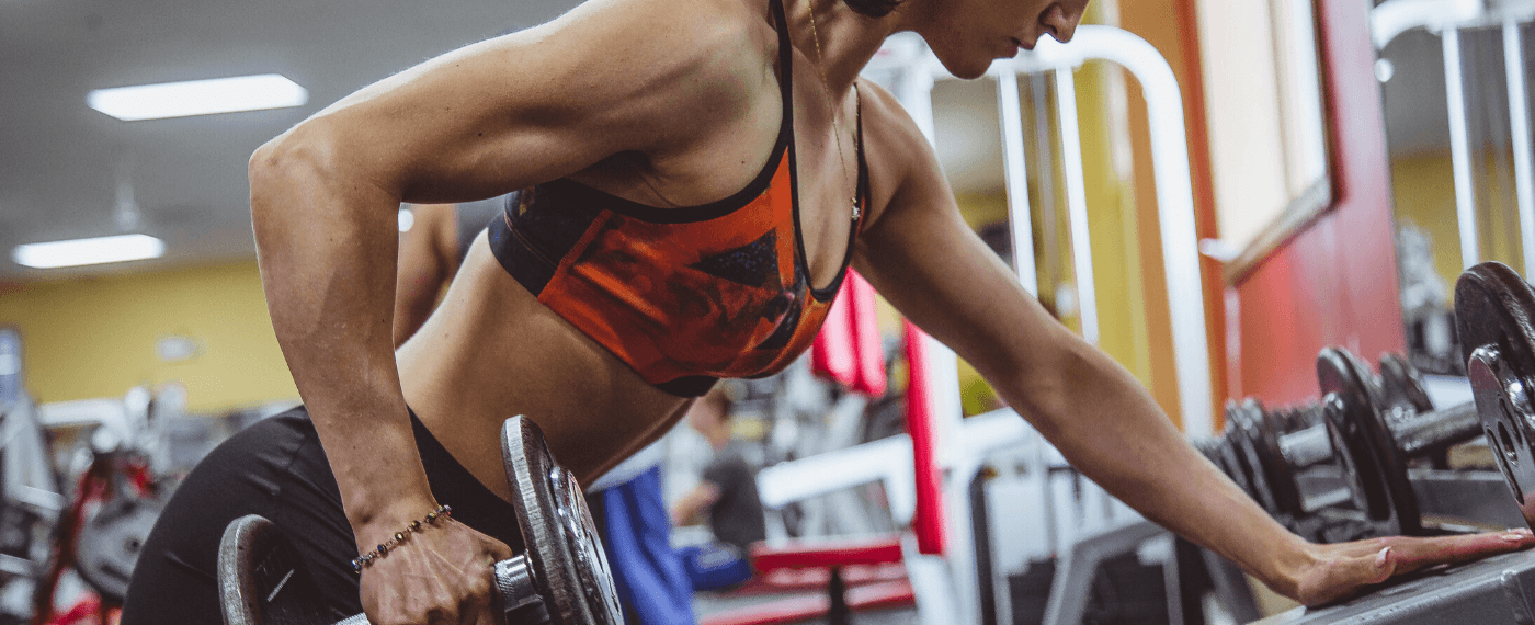 Female fitness athlete using dumbbell for back workout
