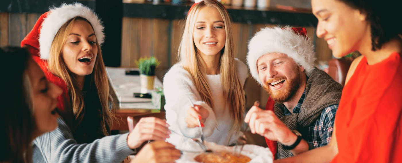 Group of friends wearing holiday hats and eating together