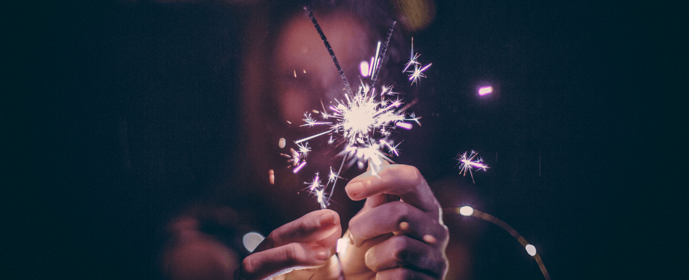 Woman holding two sparklers together creating a bright spark