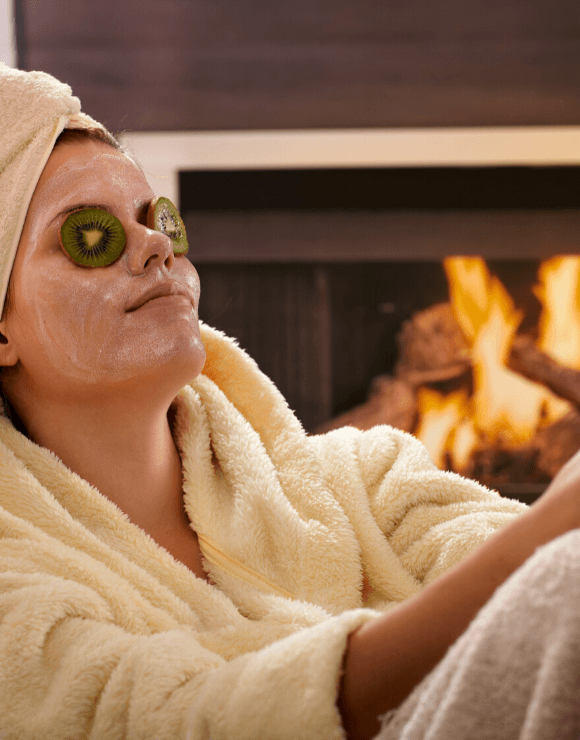 woman in spa robe with cucumber slices on her eyes and a face mask
