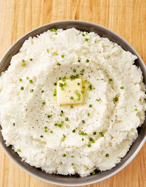 A bowl of low carb Mashed Cauliflower with a piece of melted butter in the center