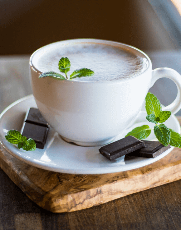 A teacup of peppermint tea with peppermint chocolates on the side