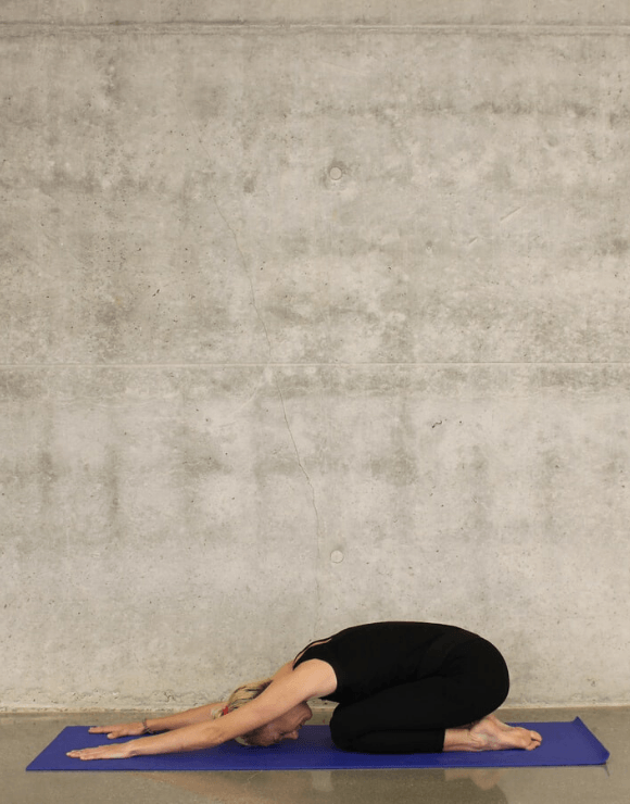 woman stretching on yoga mat with arms out in front of her to help stimulate gut health