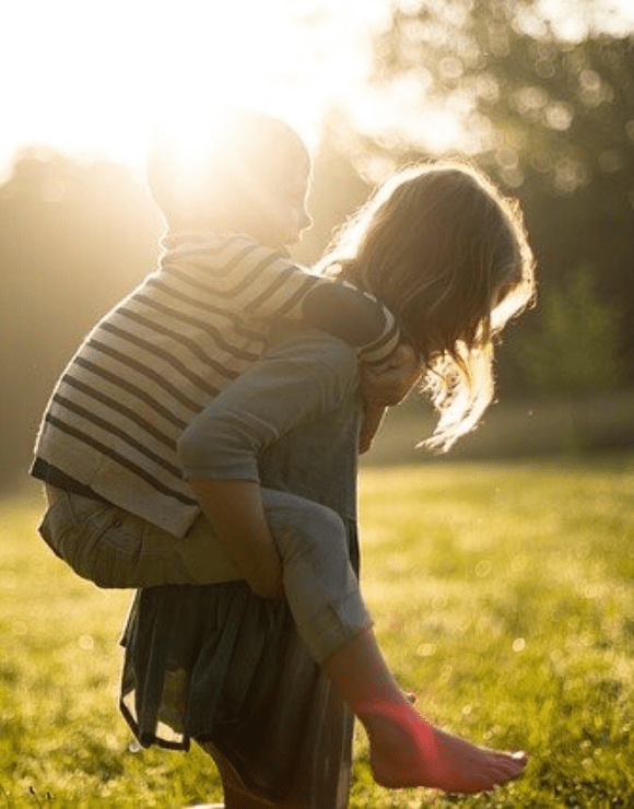 Older sister giving younger brother a piggy back ride