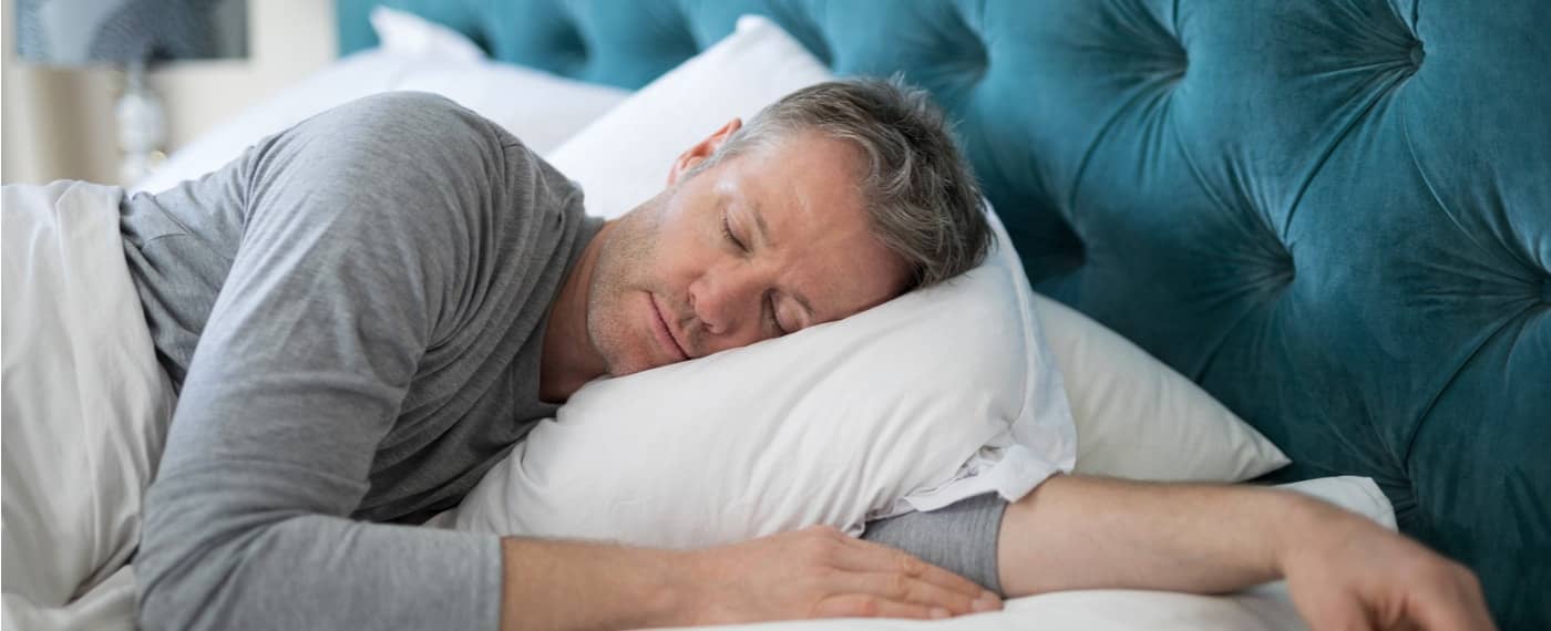 Older male sleeping with one arm under pillow after using natural sleep remedies