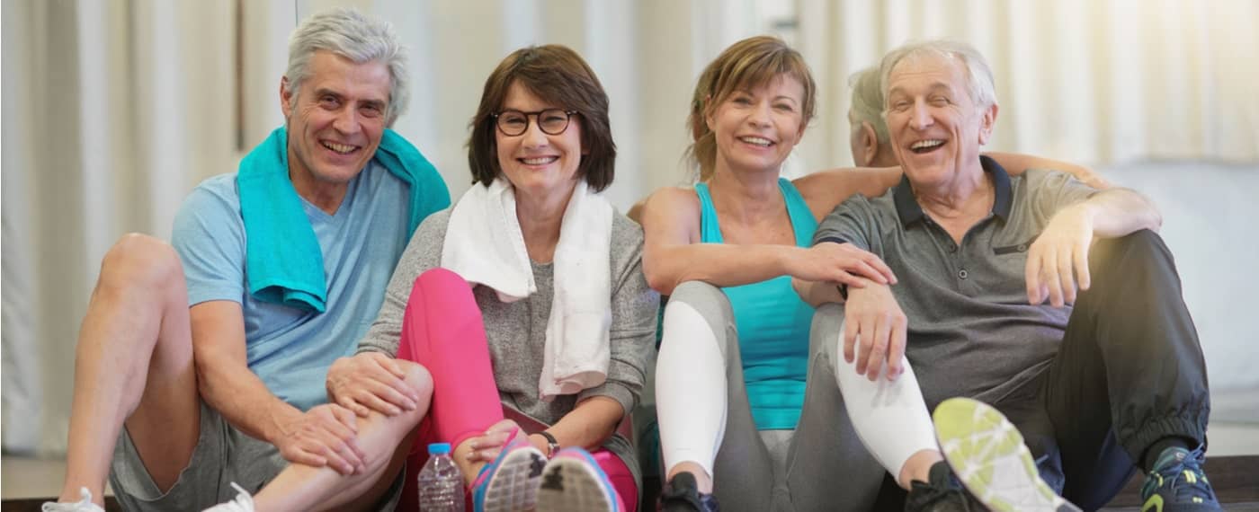 Two older married couples smiling after a yoga for arthritis pain class
