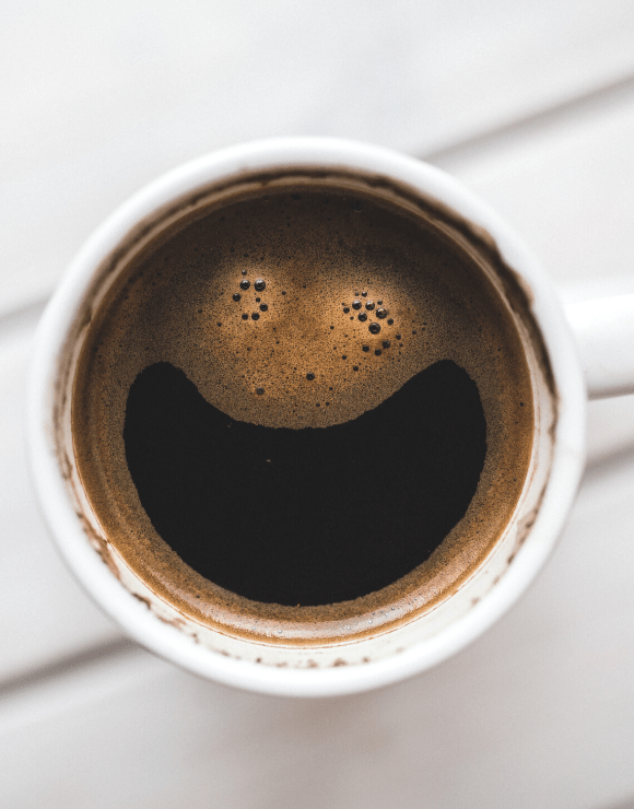 a cup of coffee with the foam forming a smiley face