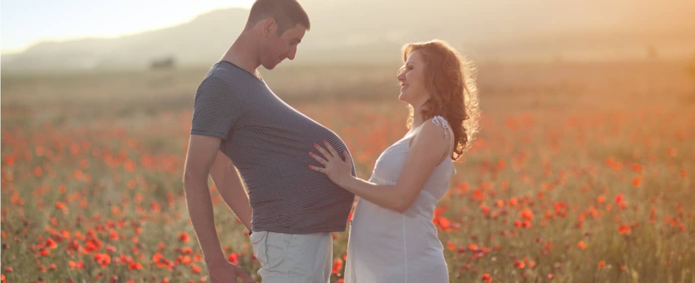 Man experiencing pregnancy belly with pregnant wife