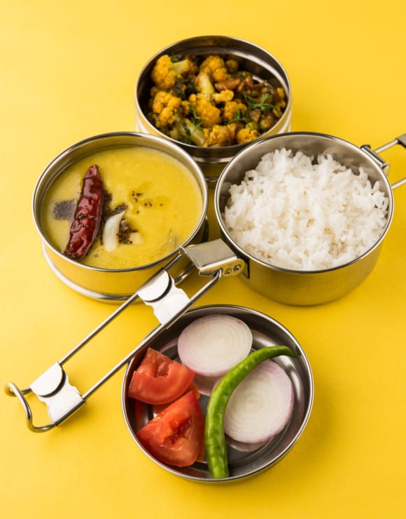 Pots and pans filled with Indian Tiffin Lunch including rice, curry, and vegetables
