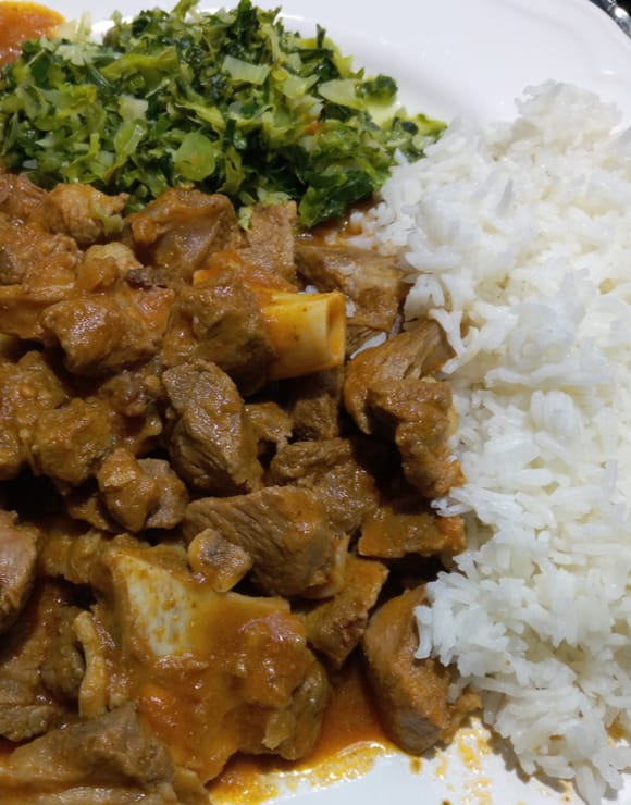 A plate of Kenyan Stews made from meat, potatoes, and vegetables served with ugali