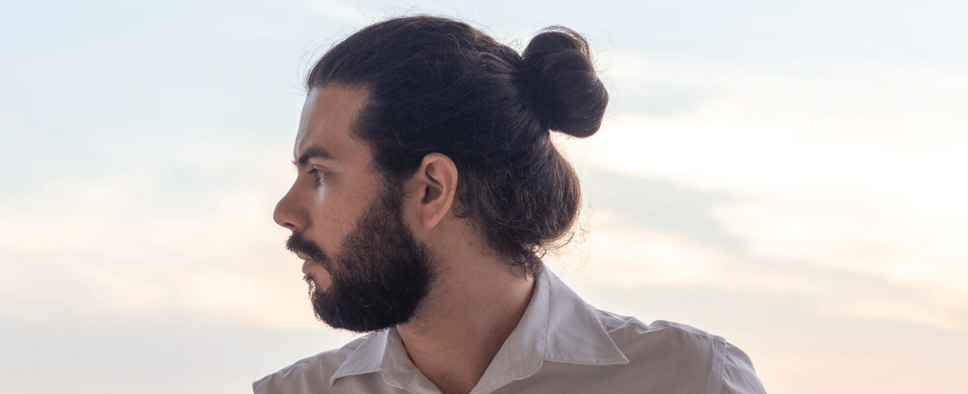 Man with beard and man-bun looking off to the side