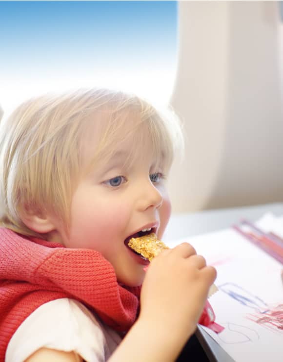 Small child enjoying a granola snack while traveling on an airplane