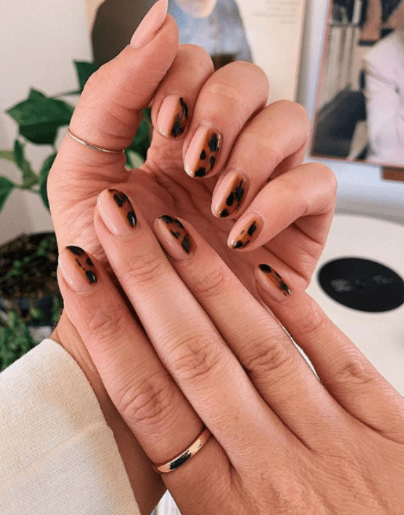 Up close view of manicured nails with leopard nail polish
