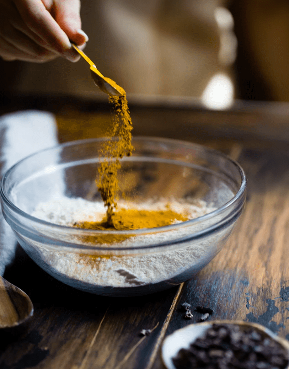 ground turmeric being sprinkled over a bowl of flour