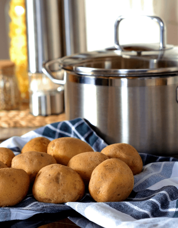 Uncooked potatoes sitting next to a cooking pot
