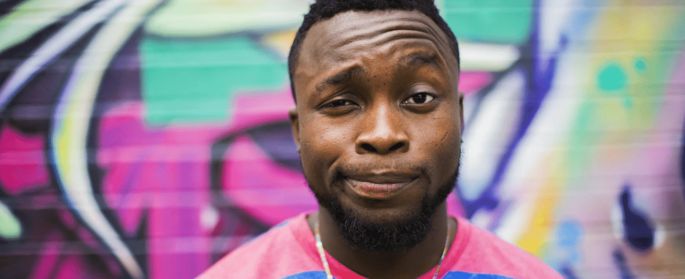 Man smirking at camera in front of graffiti background